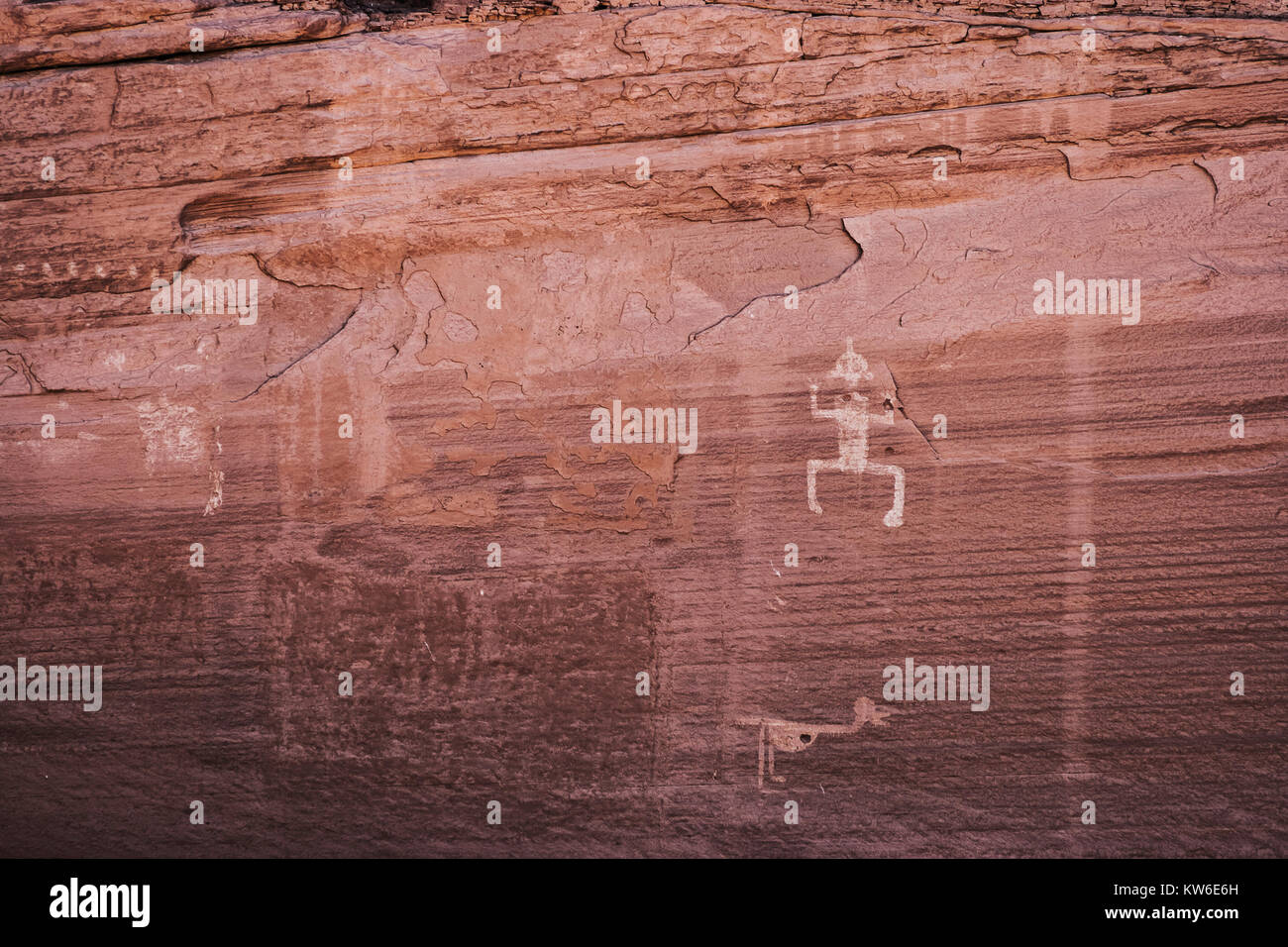 Carved Anasazi petroglyphs representing a humanoid and an animal on a sandstone cliff of the