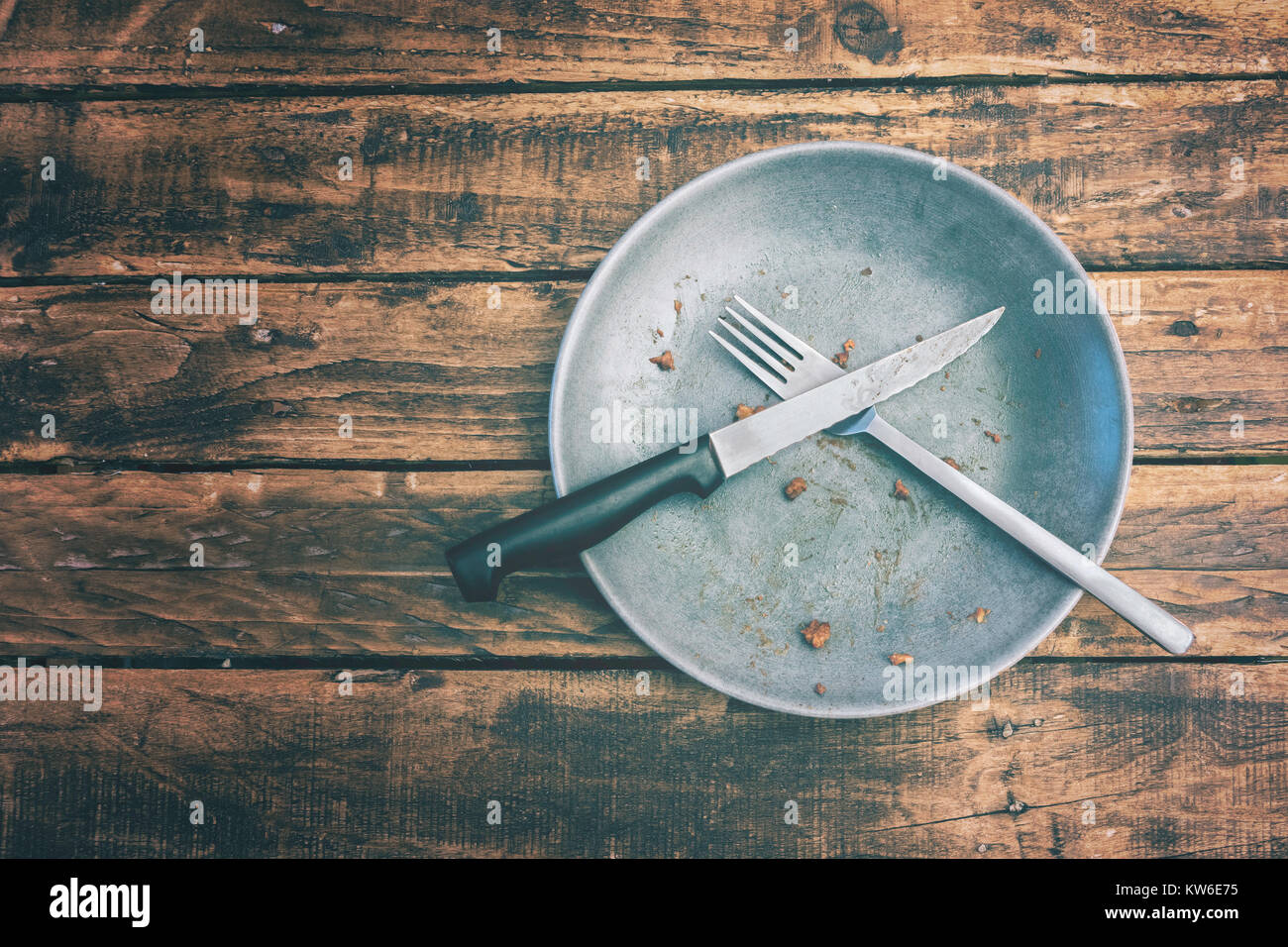 Top view or flat lay picture of a dirty plate after having eaten the dish on a grungy wooden table. Food concept. Stock Photo