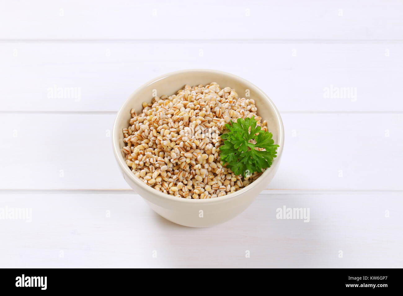 bowl of cooked pearl barley on white wooden background Stock Photo