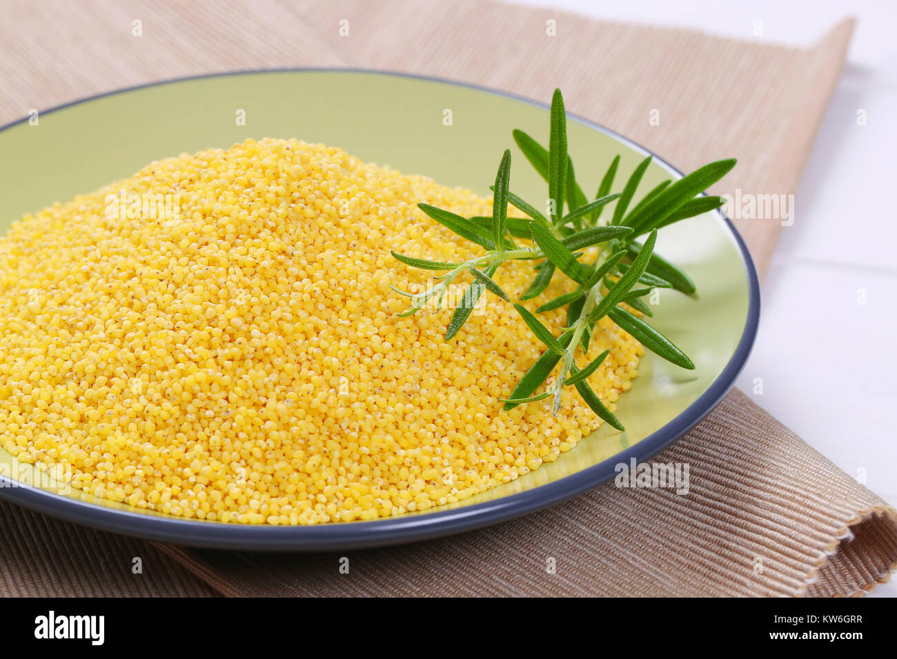 plate of raw millet on beige place mat - close up Stock Photo