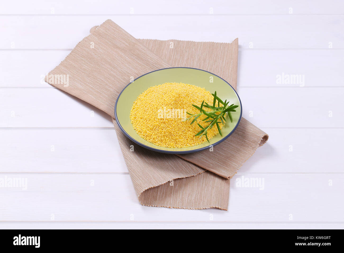 plate of raw millet on beige place mat Stock Photo