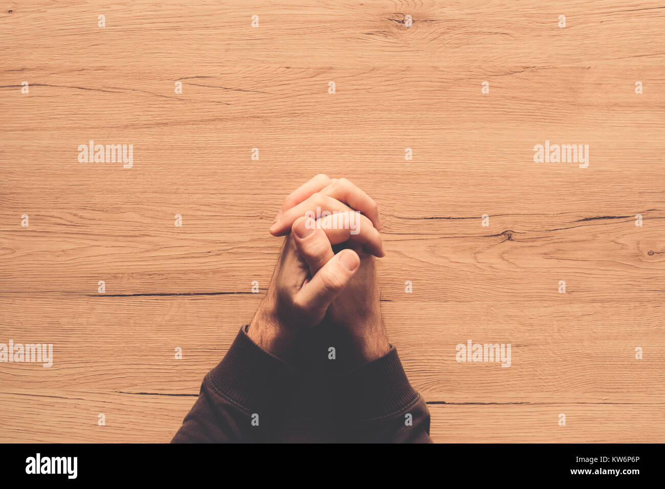 Man praying, overhead view of male hands on wooden church prayer kneeler Stock Photo