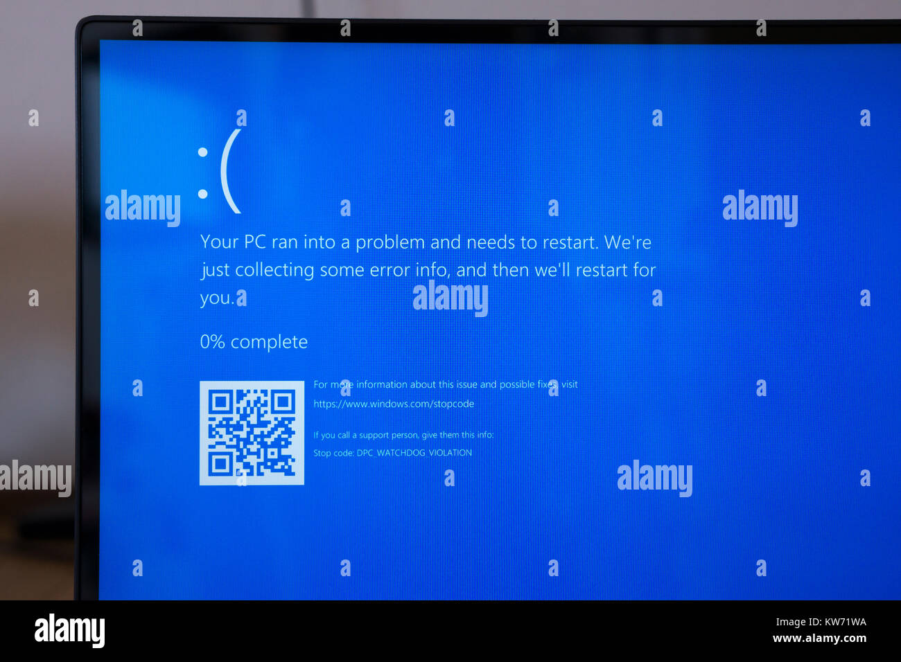 A laptop screen showing 'Your PC ran into a problem and needs to restart.' Theme - computer problems, crash, blue screen, error, broken Stock Photo