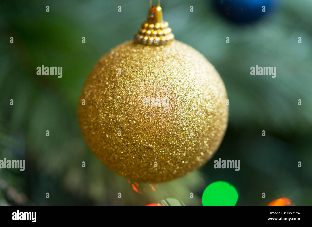 A closeup of a single yellow bauble decoration suspended from a Christmas tree Stock Photo