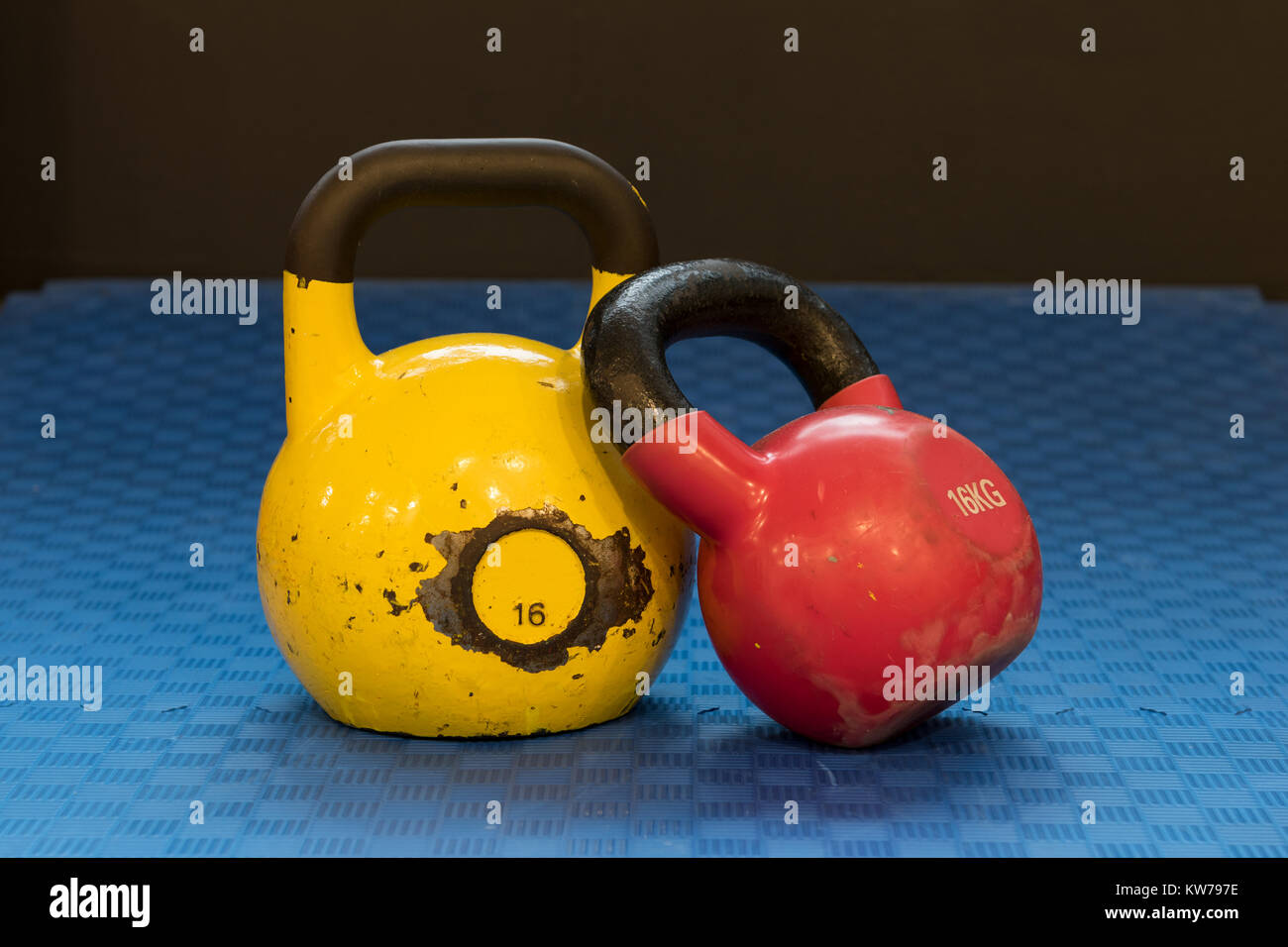 Red and yellow used and old kettlebells on a blue background. Workout  equipment Stock Photo - Alamy