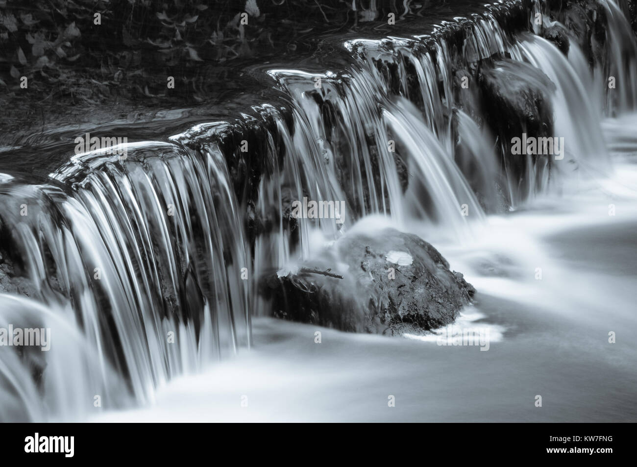 The River Dove flowing over a small weir in the secluded woodland valley of Beresford Dale in the Peak District national park, England, UK Stock Photo