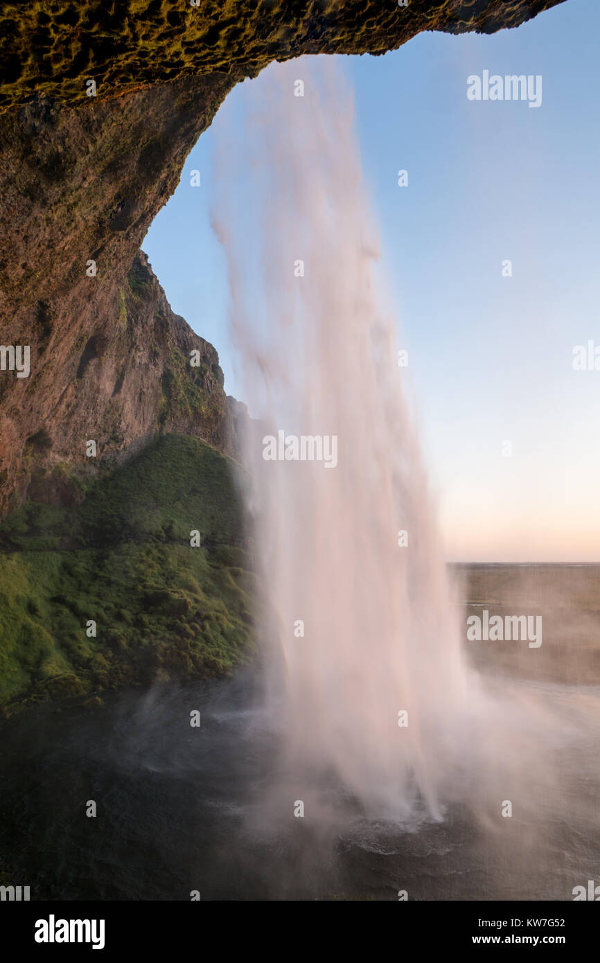 At the back of Seljalandsfoss waterfall in south of Iceland during sunset. Stock Photo