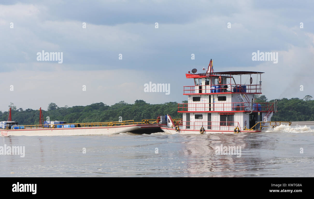 A three decked tug boat tows a barge  past rain forest on the Napo River near Coca or Puerto Francisco de Orellana. Coca, Puerto Francisco de Orellana Stock Photo
