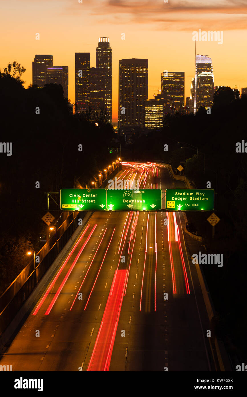 Light streaks from brake lamps flow across the foreground ad sunset falls on Los Angeles Stock Photo