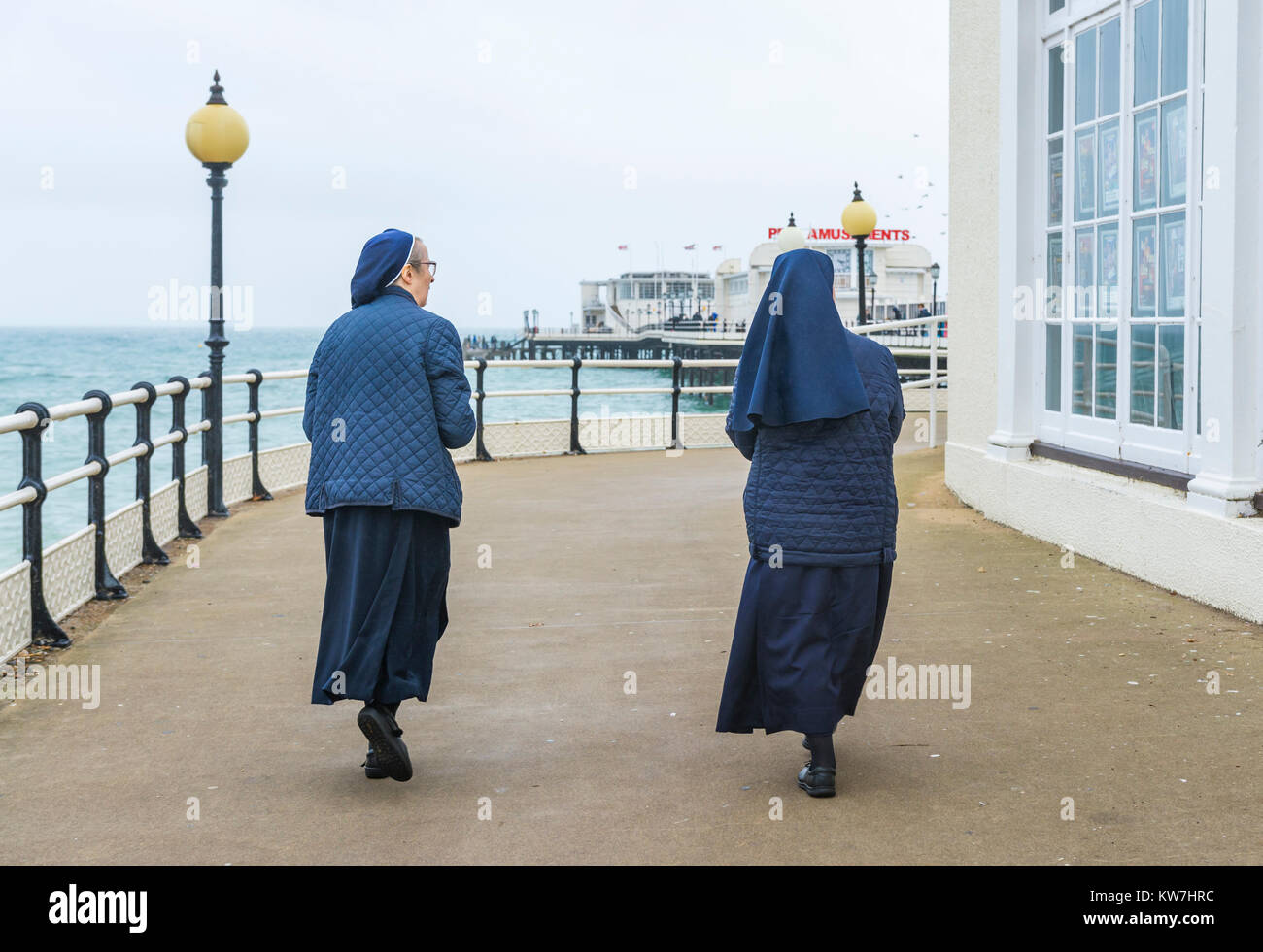 Pair of nuns walking on a pier at the seaside in England, UK. Stock Photo