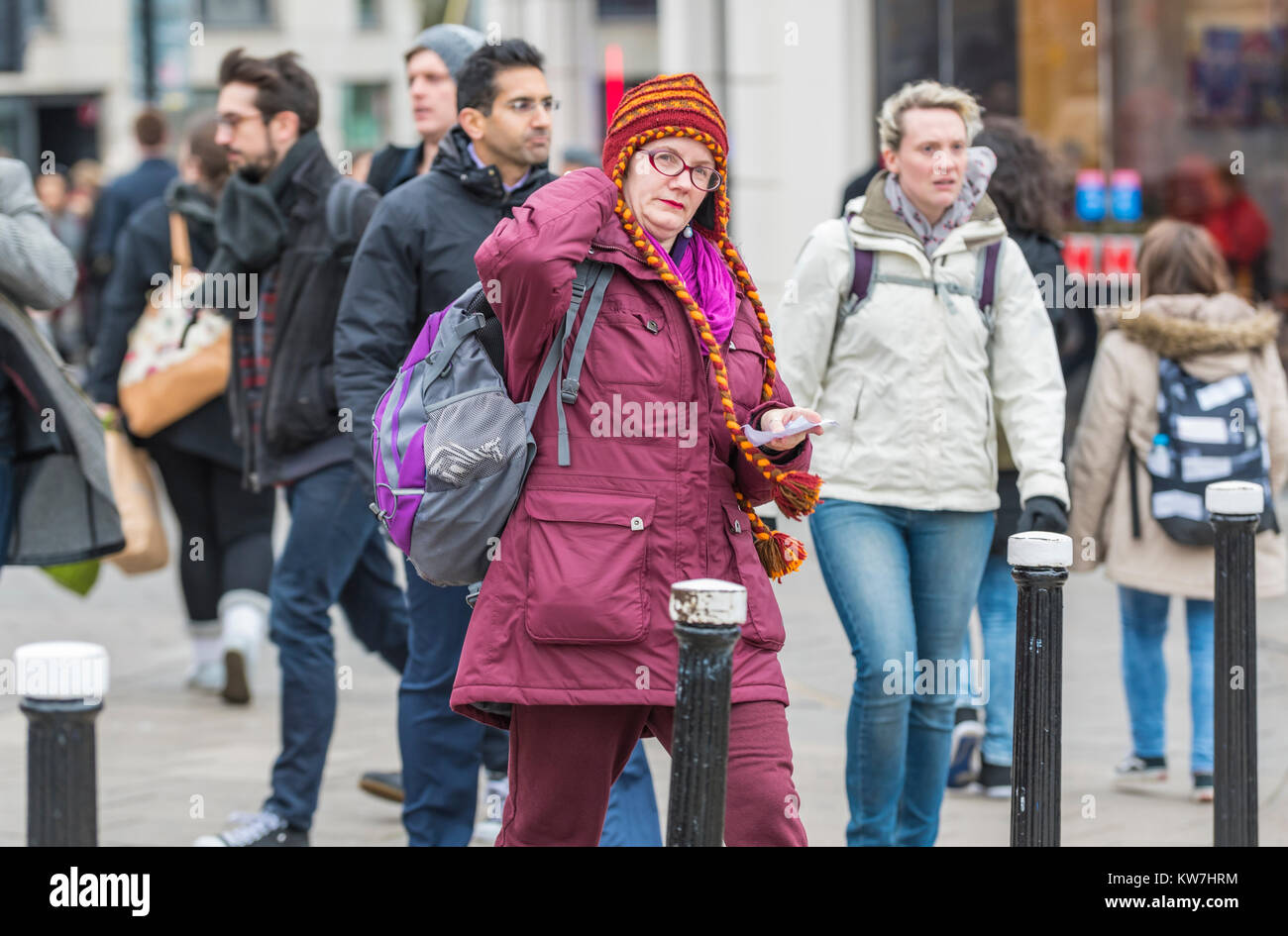 Woman wearing hand knitted colourful woolen chullo hat with braided earflaps in Winter in the UK. Stock Photo