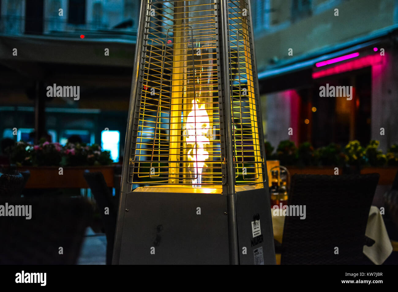 The flame from a patio heater warms a small outdoor, sidewalk cafe late at night in Split Croatia Stock Photo