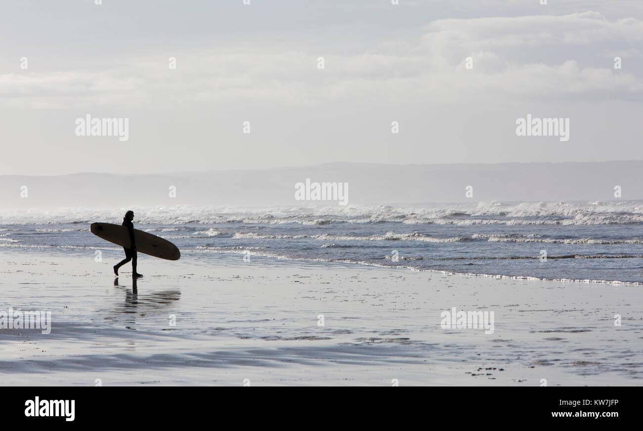 Surfer Walks on a Sandy Beach Holding a Surf Board Stock Photo