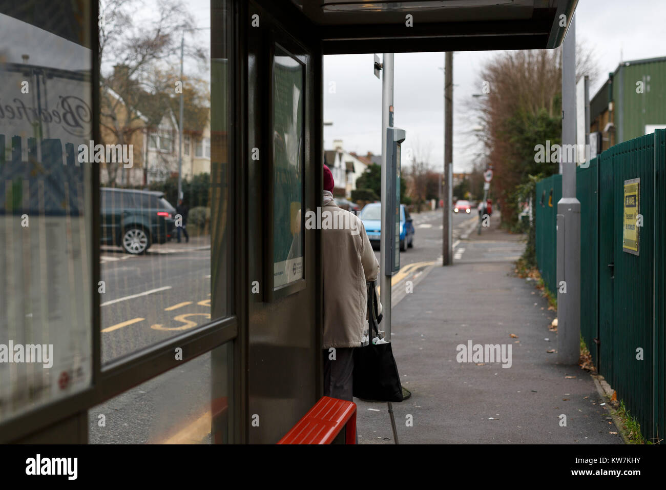 Woman waiting at bus stop on Hainault Road, Leytonstone, London. Stock Photo