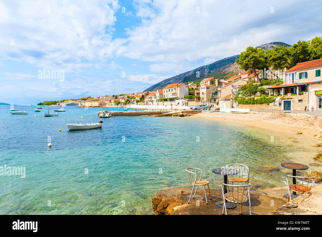 Metal cafe chairs on beach in Bol port with typical town architecture, Brac island, Croatia Stock Photo