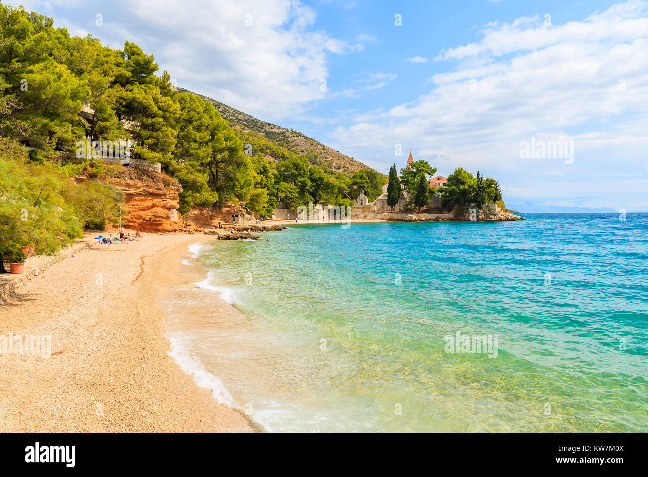 Beach with emerald green sea water and view of Dominican monastery in distance, Bol town, Brac island, Croatia Stock Photo