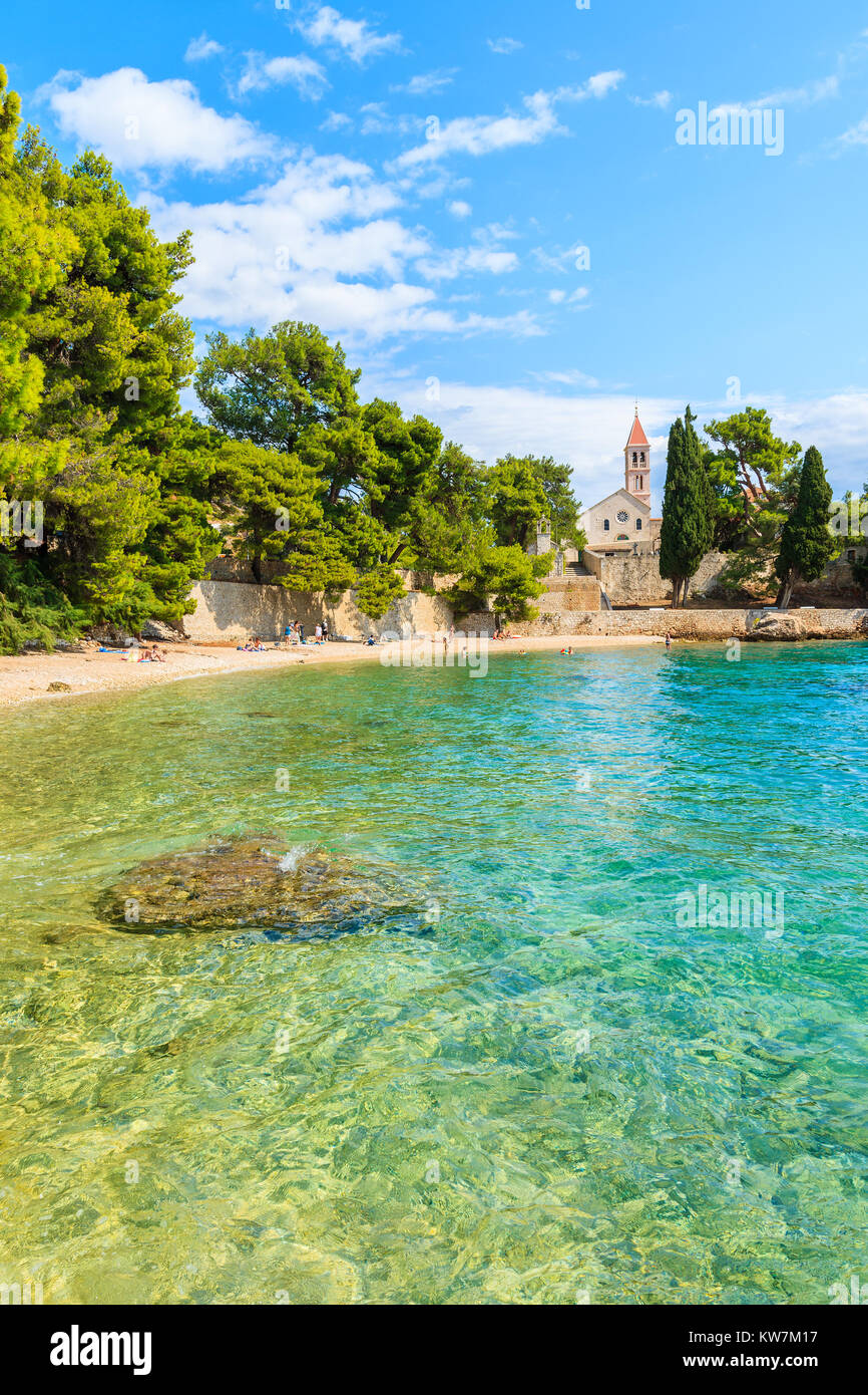 Beach with emerald green sea water and view of Dominican monastery in distance, Bol town, Brac island, Croatia Stock Photo