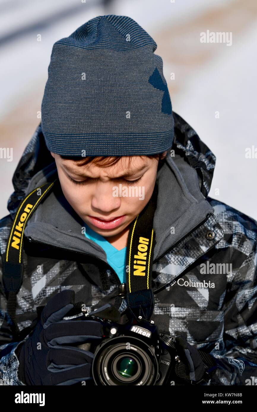 Young teenage male outside during winter taking photos with a Nikon DSLR camera Stock Photo