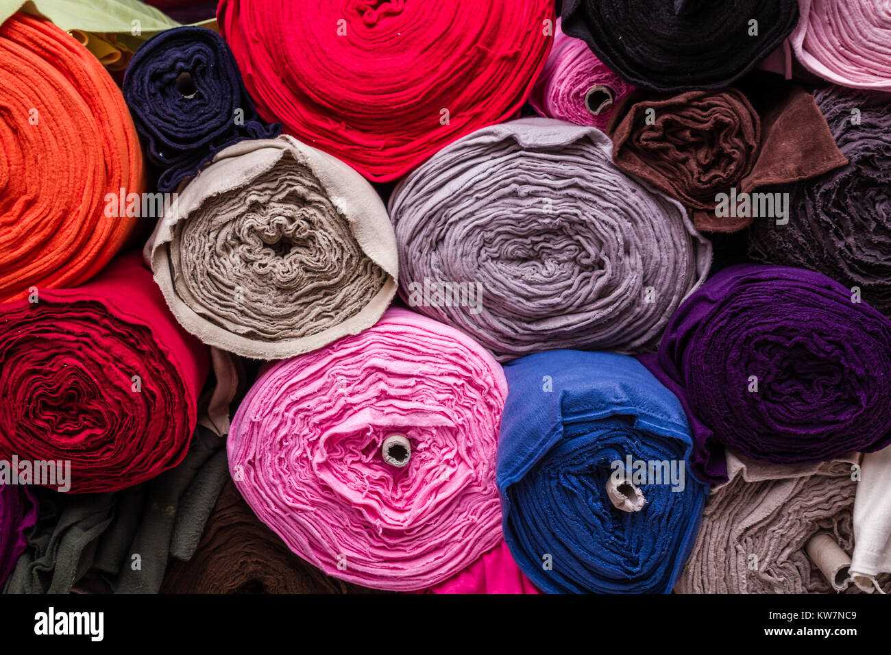 Colorful plain cotton fabric rolls on a fabric shop shelf Stock Photo