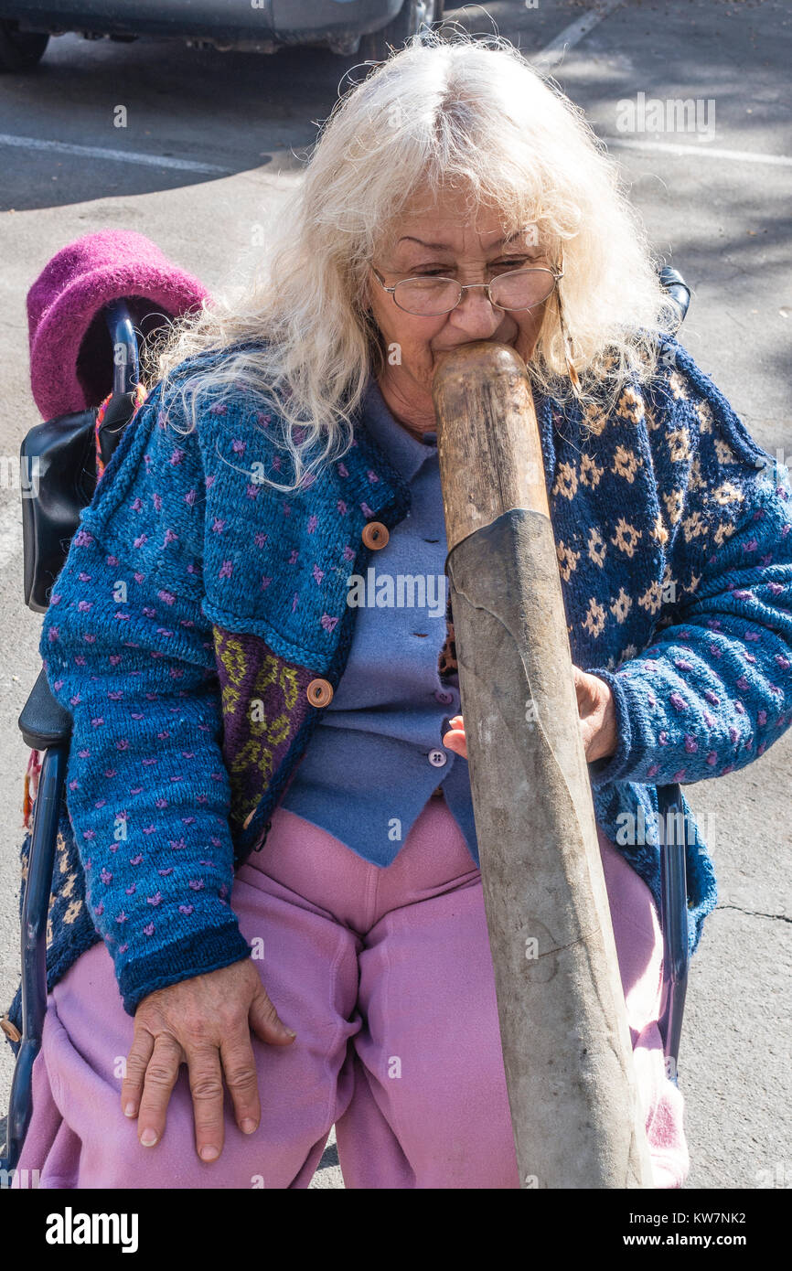 Woman playing didgeridoo at the Santa Barbara, California farmer's market. The didgeridoo (also known as a didjeridu) is a wind instrument. Stock Photo