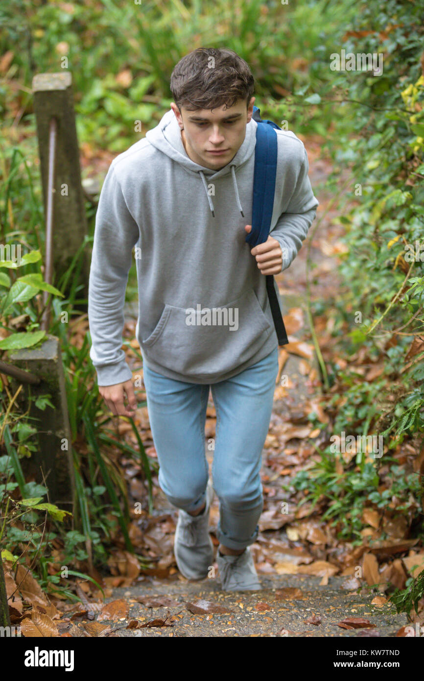 Teenage boy walking up concrete steps near a canal on an autumn day Stock Photo