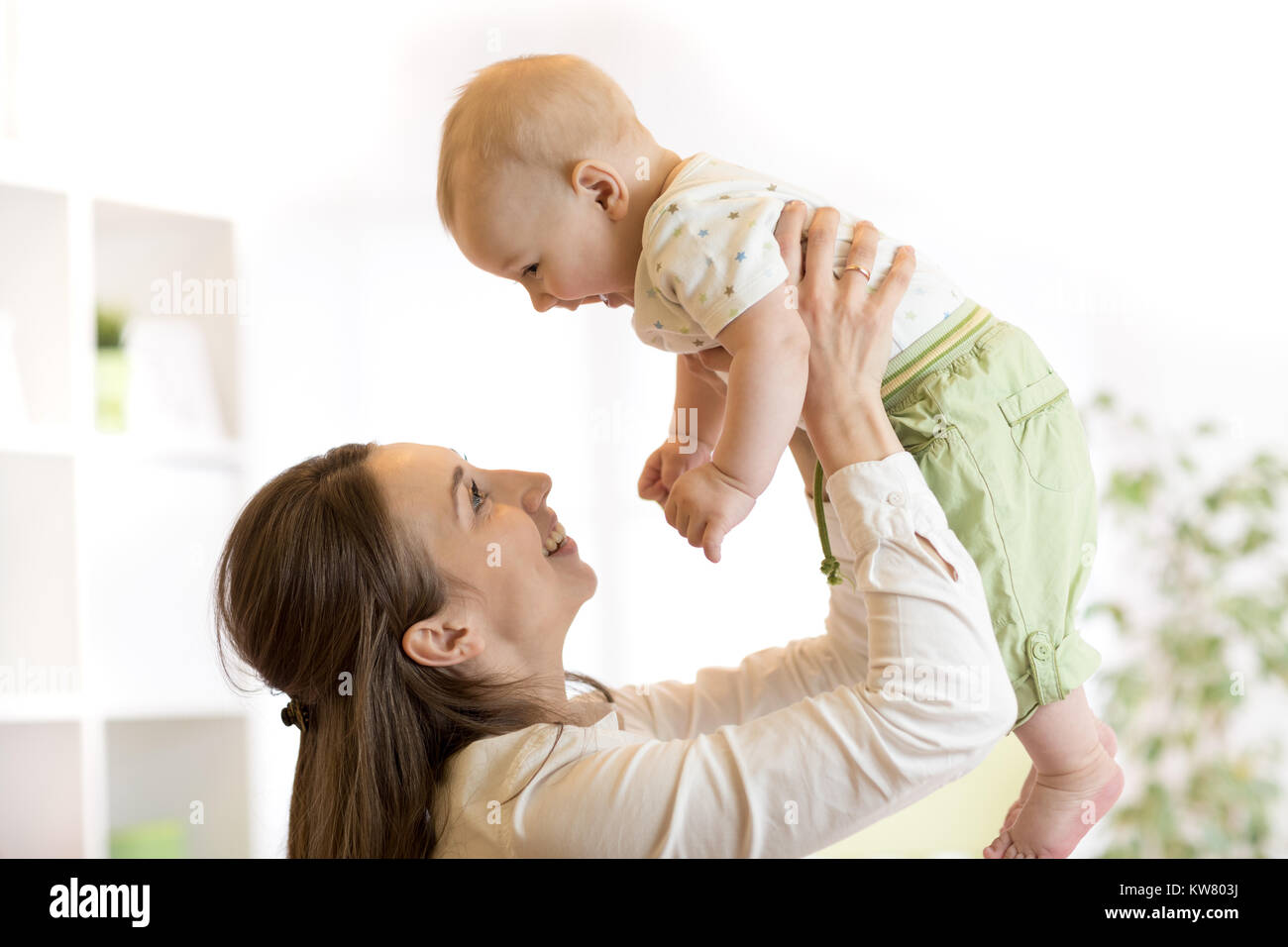 Happy mother raising baby and talking with him Stock Photo