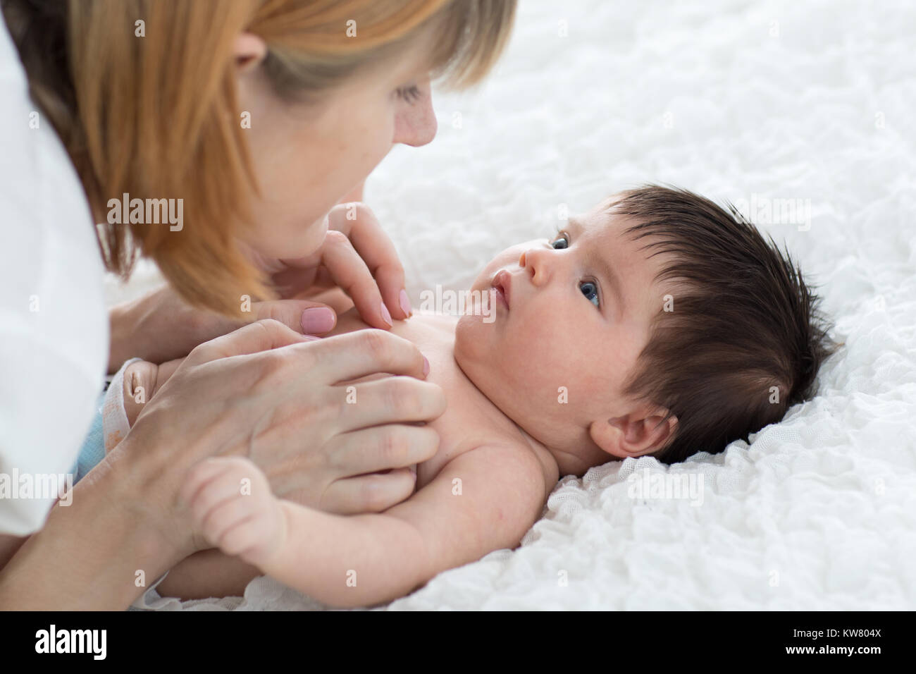 Happy mother looking at baby in bedroom Stock Photo