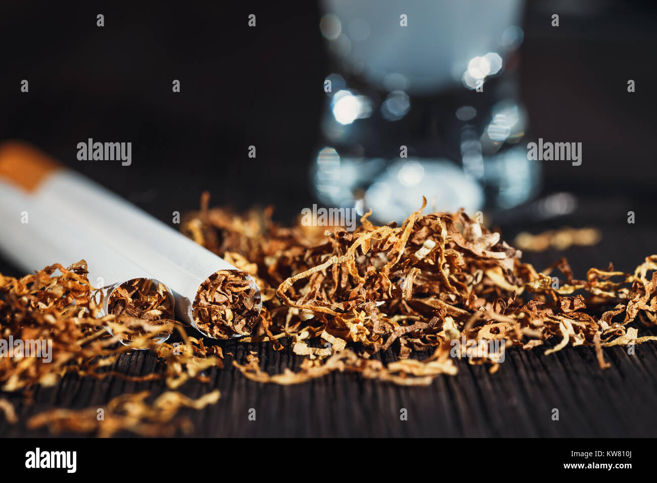 hand made cigarette and tobacco with a glass of vodka in the background  Stock Photo