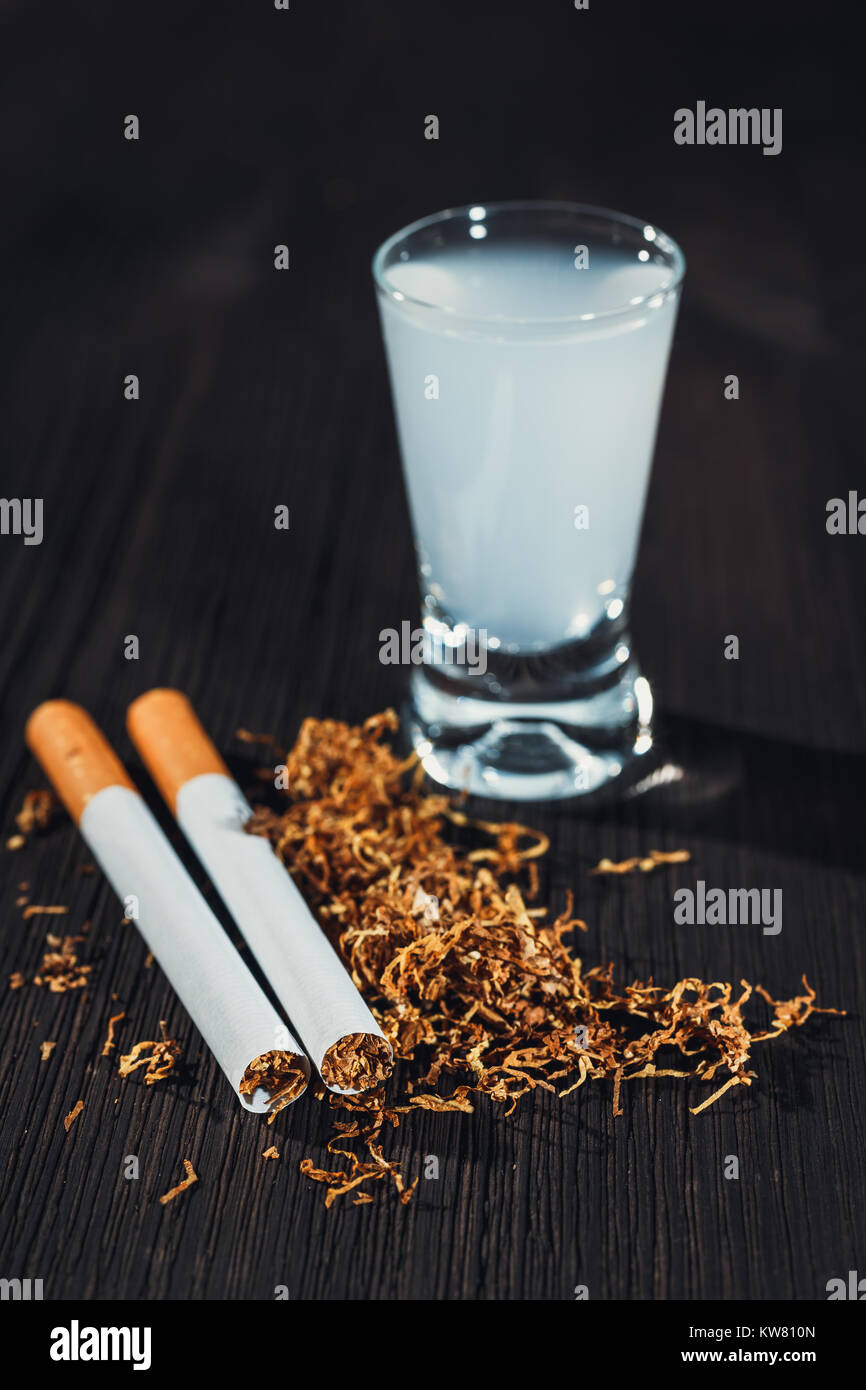 hand made cigarette and tobacco with a glass of vodka in the background  Stock Photo