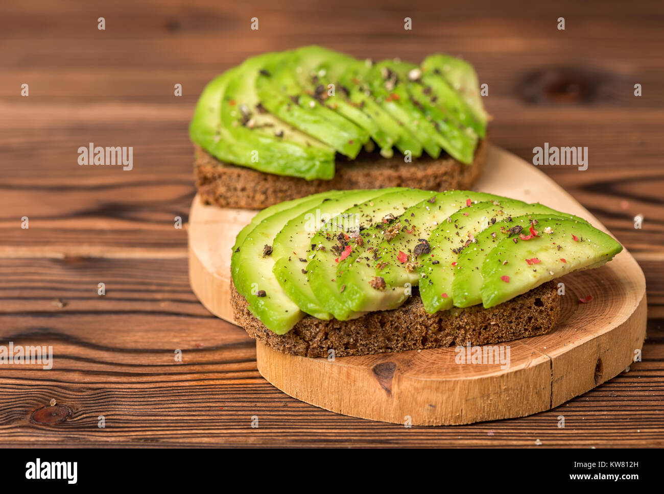 avocado sandwiches with cutted rye bread and sprinkle with pepper on wooden background, healthy eating Stock Photo