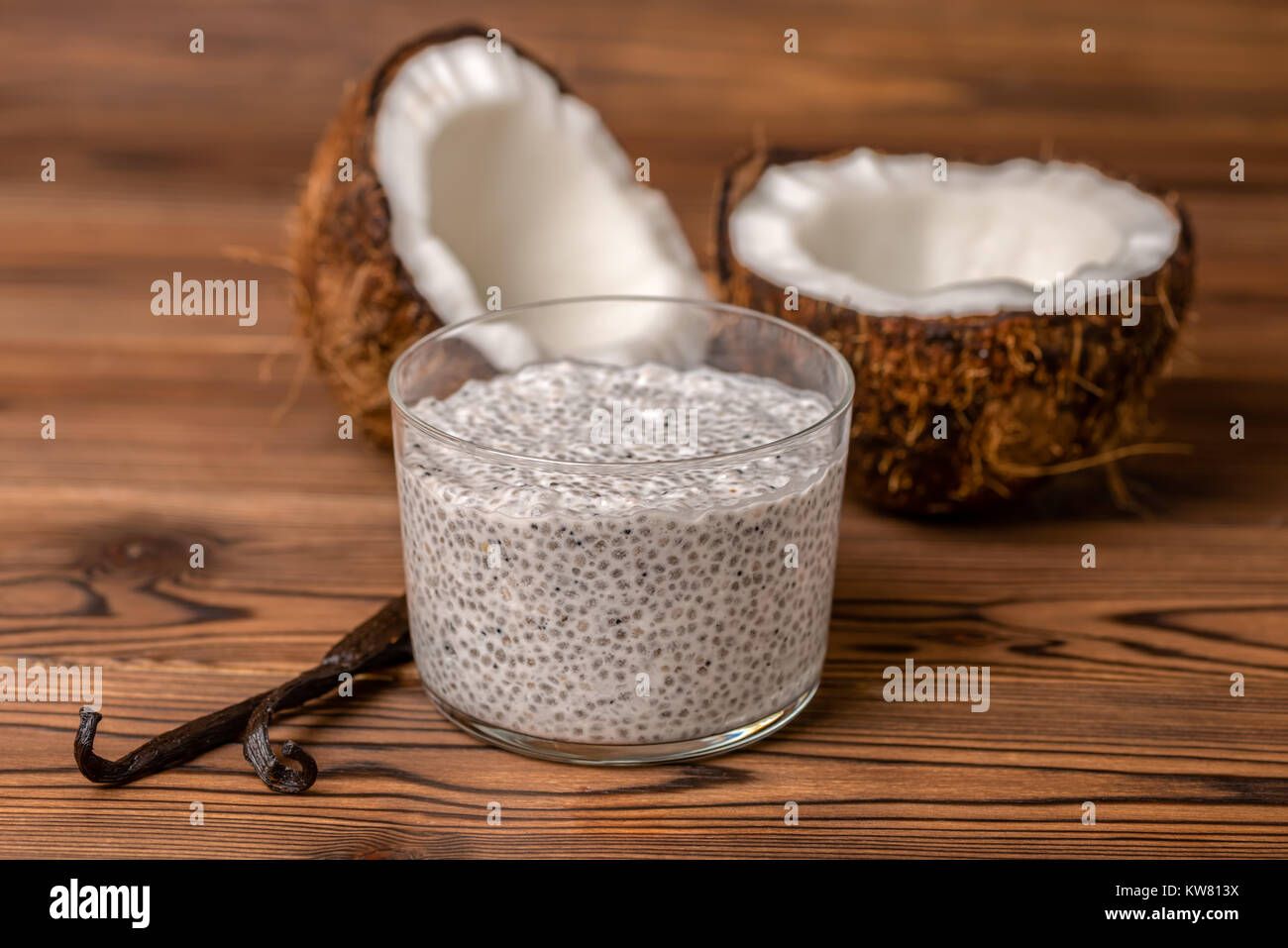 chia pudding in glass, decorated  vanilla pods and coconuts on wooden background, healthy lifestyle concept Stock Photo