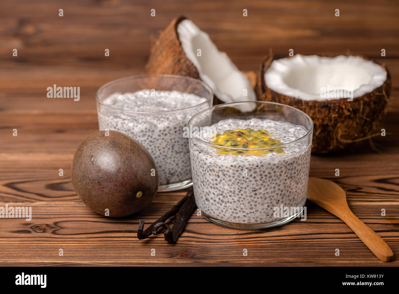 chia pudding in glass, decorated  vanilla pods, passionfruit and coconuts on wooden background, healthy detox lifestyle concept Stock Photo