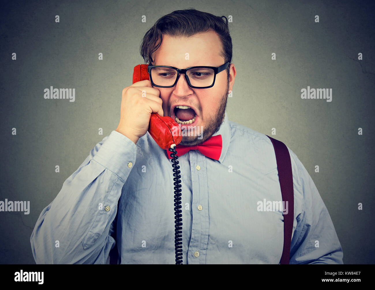 Young chubby man in formal clothing shouting in phone while having talk. Stock Photo