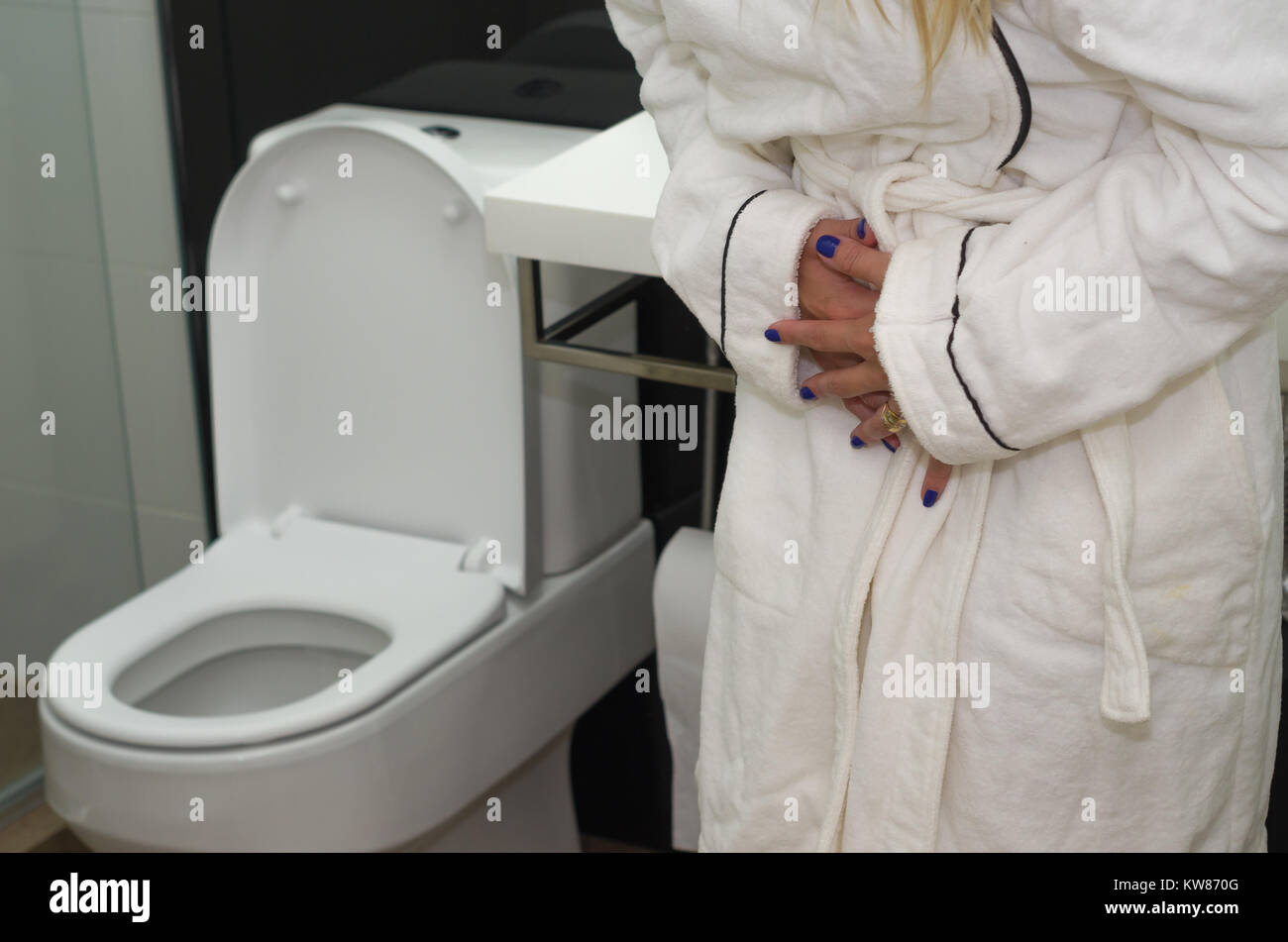Young blonde woman getting sick, with nausea in the bathroom Stock