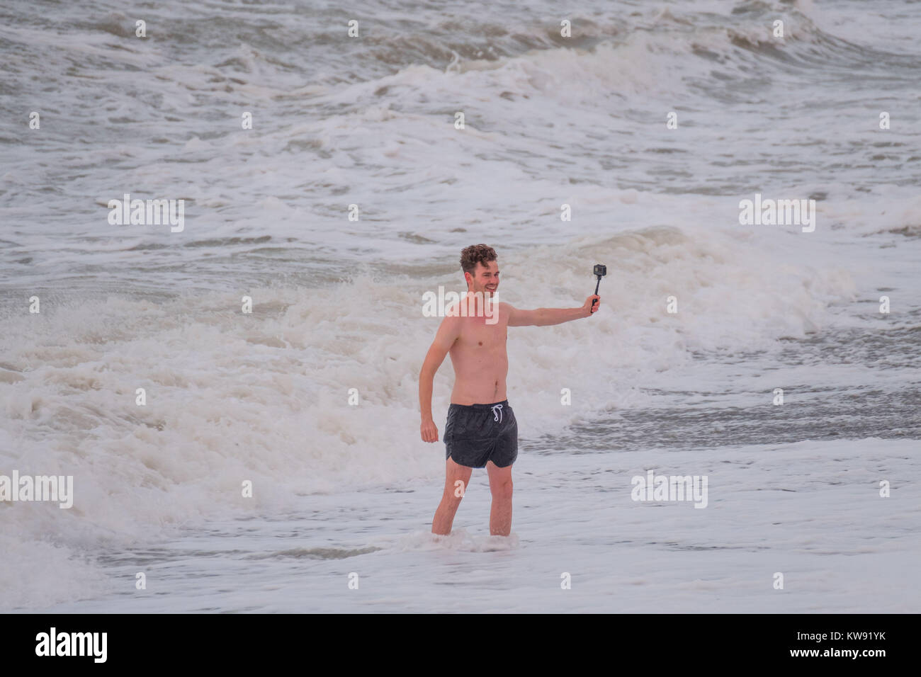 Aberystwyth Wales UK New Years Day, Monday 01 January 2018 UK Weather: On the first day of the New Year, January 1 2018, a man braves the strong winds and the icy cold water in the sea in Aberystwyth to take a selfie. The weather is set to deteriorate over the next 48 hours, with winds gusting in excess of 50mph on Tuesday night and Wednesday morning photo Credit: Keith Morris/Alamy Live News Stock Photo