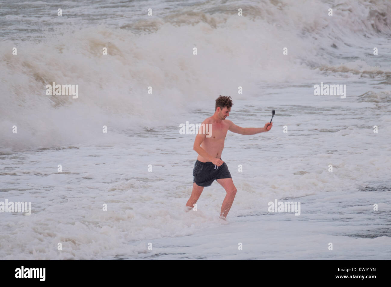 Aberystwyth Wales UK New Years Day, Monday 01 January 2018 UK Weather: On the first day of the New Year, January 1 2018, a man braves the strong winds and the icy cold water in the sea in Aberystwyth to take a selfie. The weather is set to deteriorate over the next 48 hours, with winds gusting in excess of 50mph on Tuesday night and Wednesday morning photo Credit: Keith Morris/Alamy Live News Stock Photo