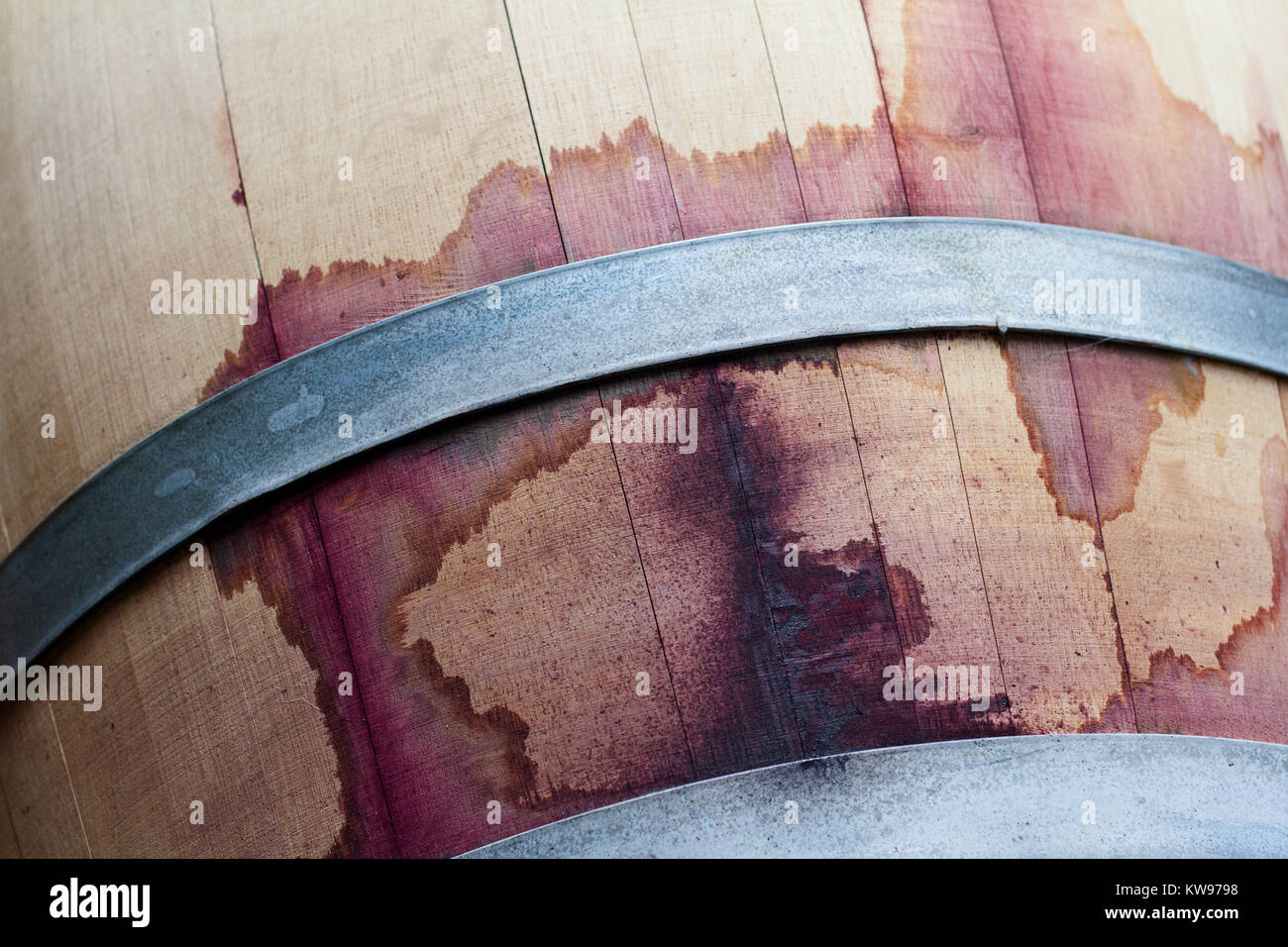 front view closeup of a wine oak wood barrel texture stained with red tannins Stock Photo