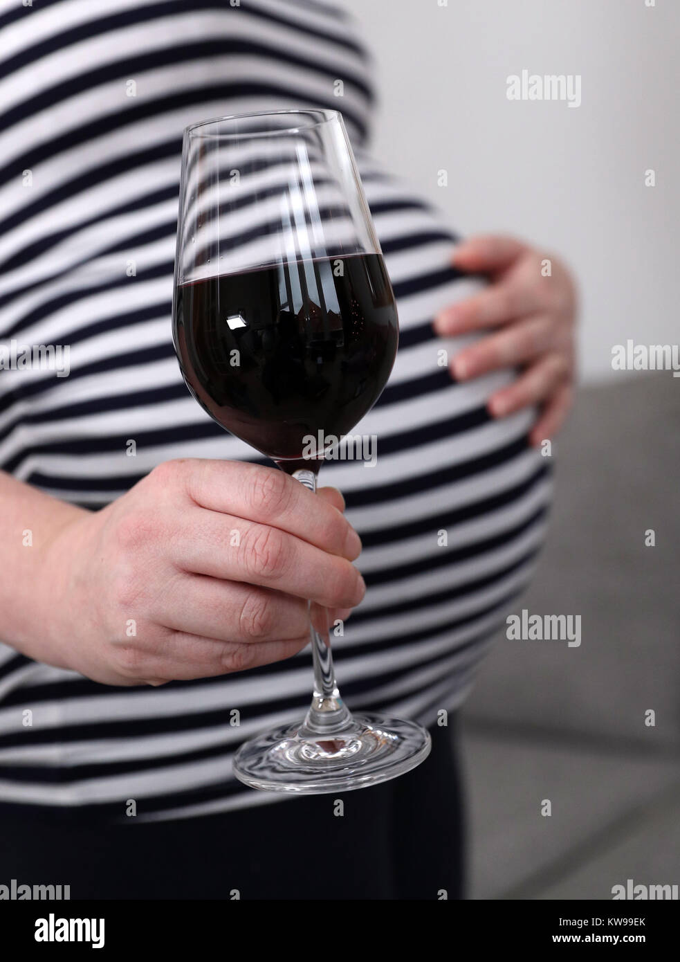 POSED BY MODEL A pregnant woman holds a glass of red wine in her hand
