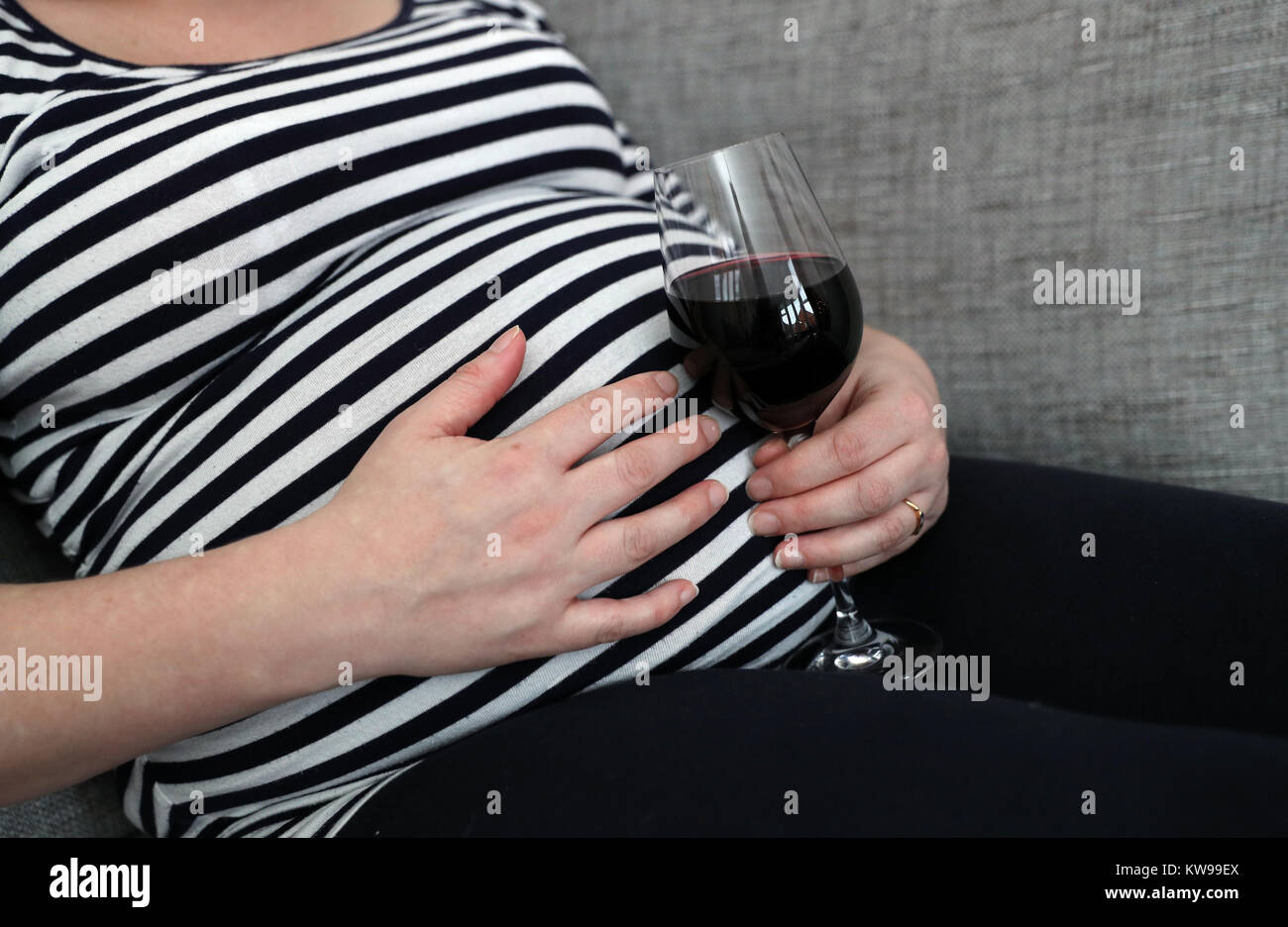 POSED BY MODEL A pregnant woman holds a glass of red wine in her hand