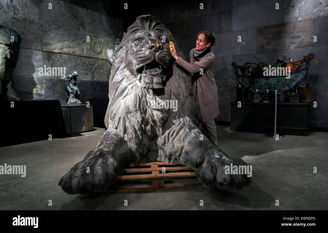 Kate Diment from Summers Place Auctions, polishes one of a pair of giant bronze lions in the style of those which famously guard Trafalgar Square, modelled on the originals designed by artist Sir Edwin Landseer which surround Nelson's Column, which could sell for up to £100,000 at auction, when they go under the hammer in Billingshurst, West Sussex, in March. Stock Photo