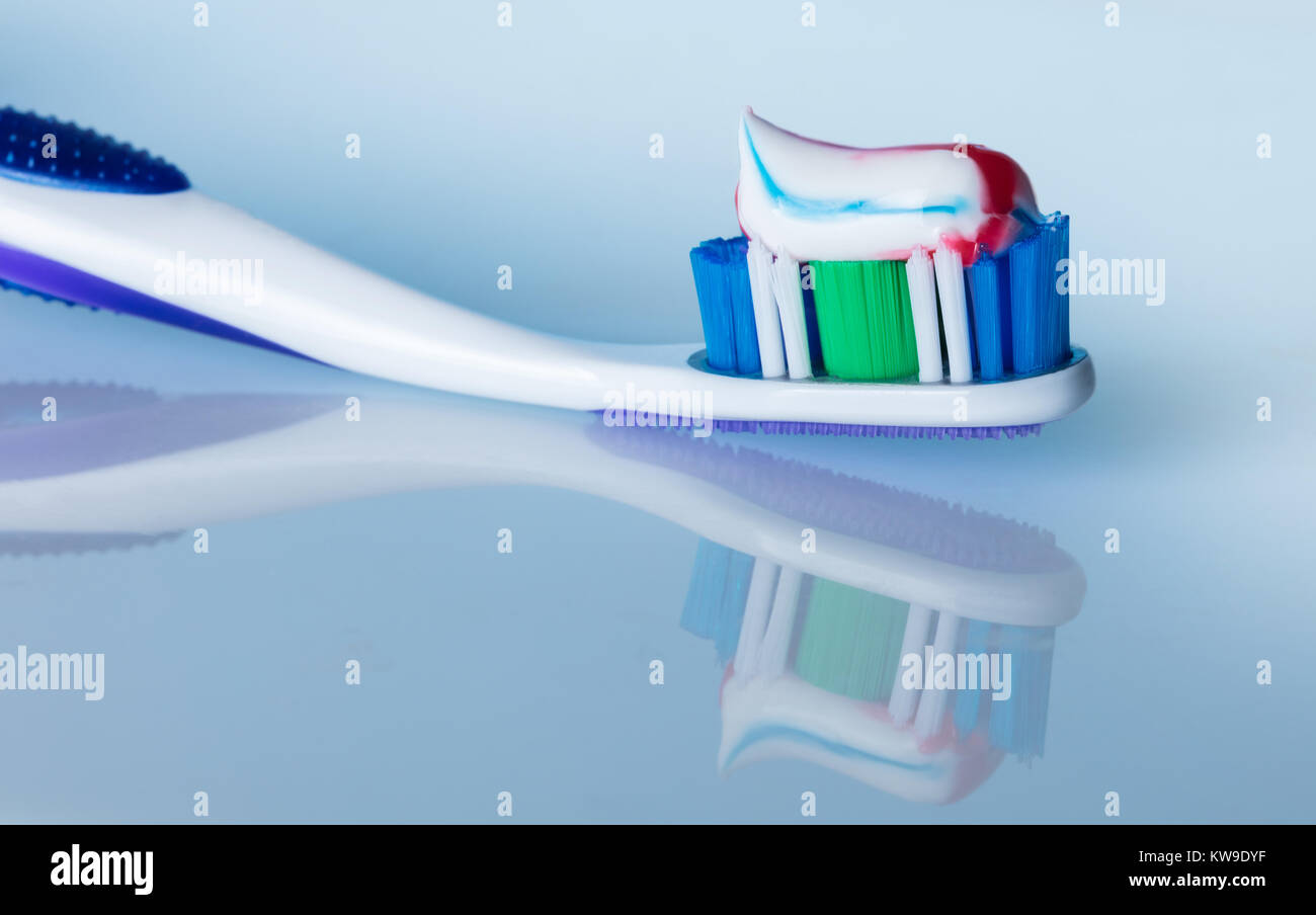 toothbrush with paste on a blue background with reflection Stock Photo