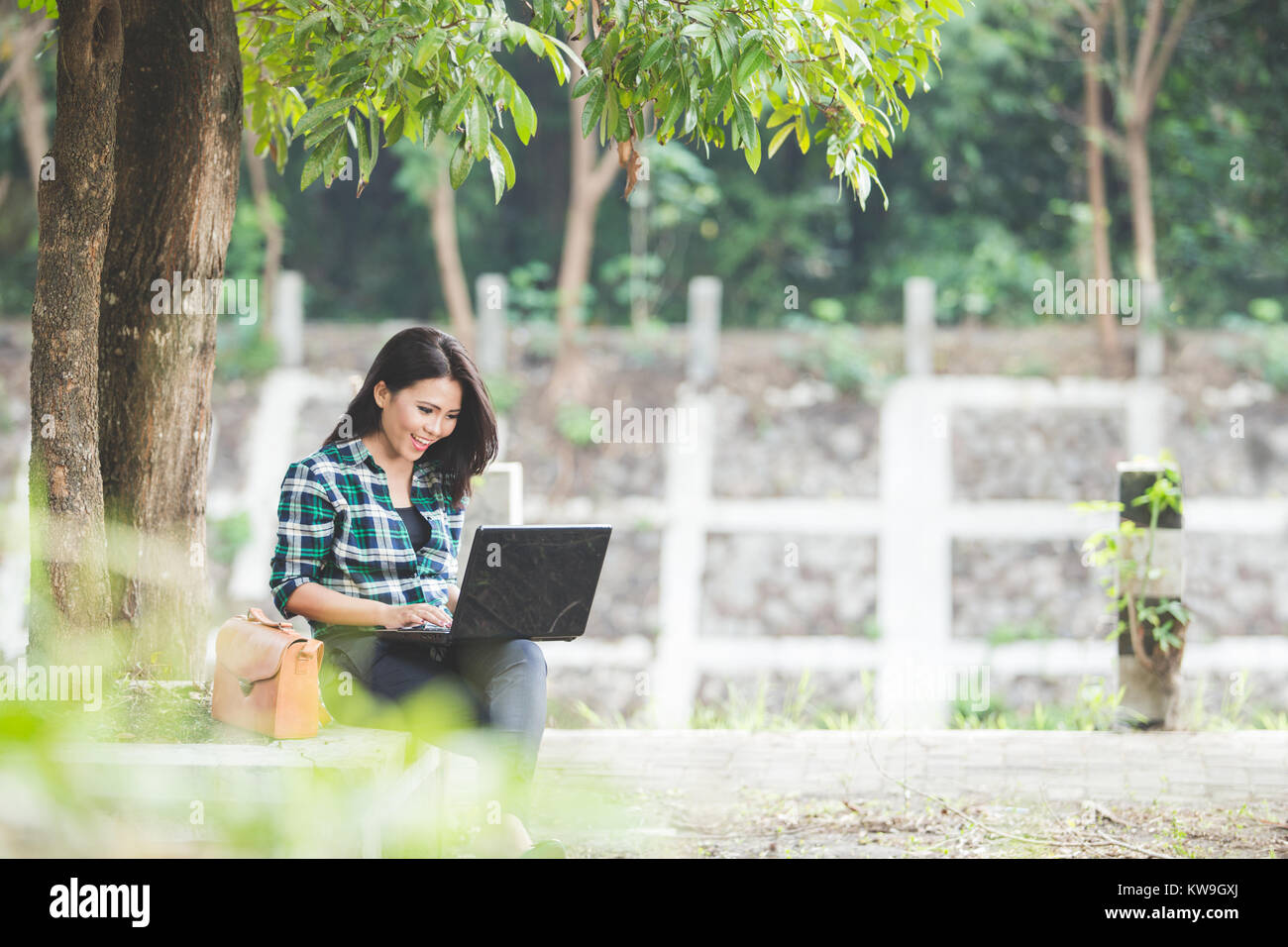 A portrait of a young asian woman using laptop while sitting on the ...