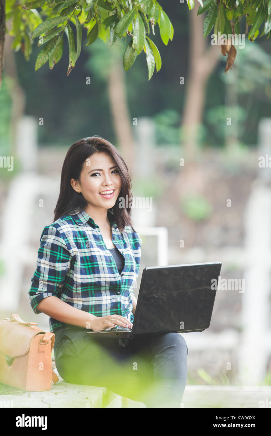 A portrait of a young asian woman using laptop while sitting on the ...