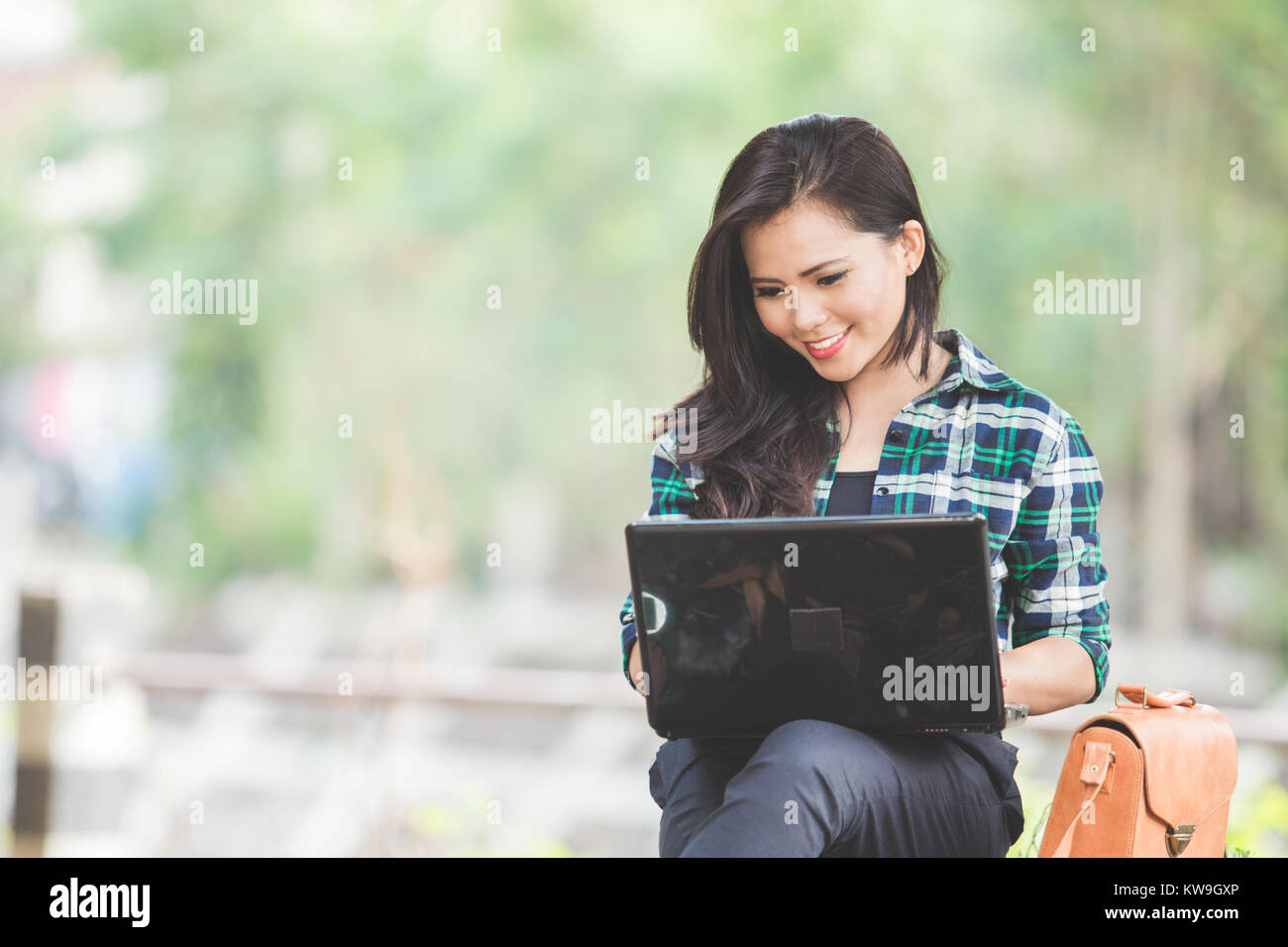 A portrait of a young asian woman using laptop while sitting on the ...