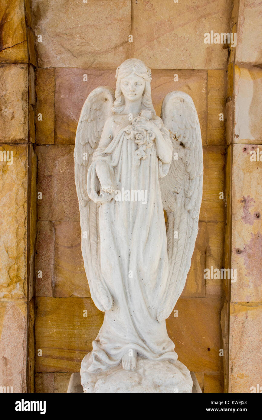 Old white angel statue in the church with stone wall background. Stock Photo