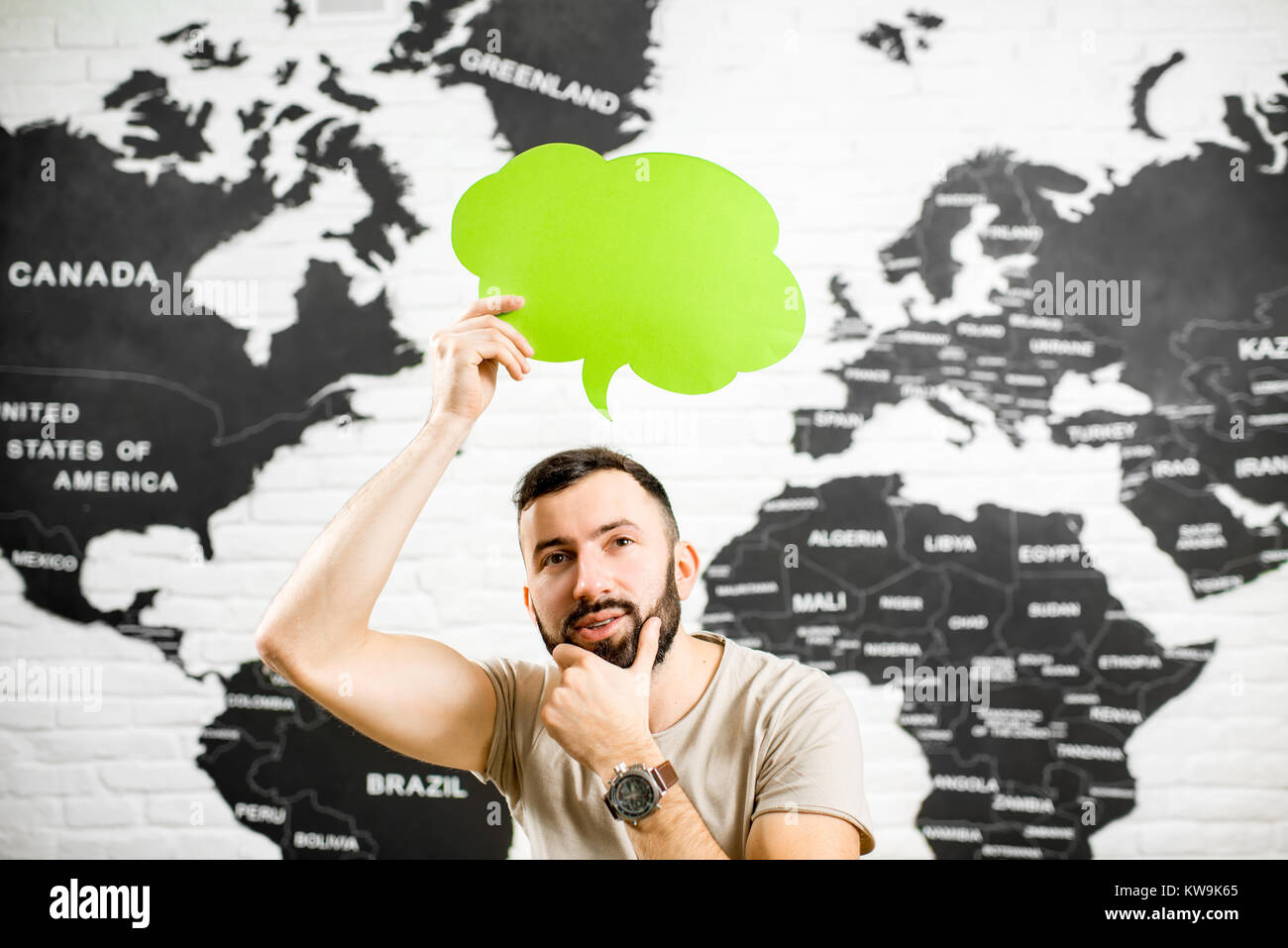 Man holding a colorful bubble above the head sitting at the office with world map on the background dreaming about traveling Stock Photo