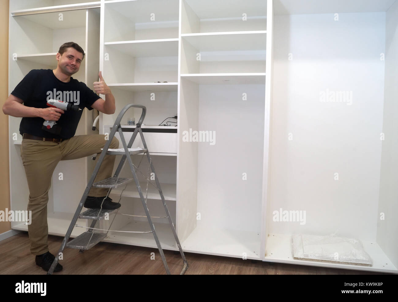 Smiling Service man at the time of assembling of built-in wardrobe. Stock Photo