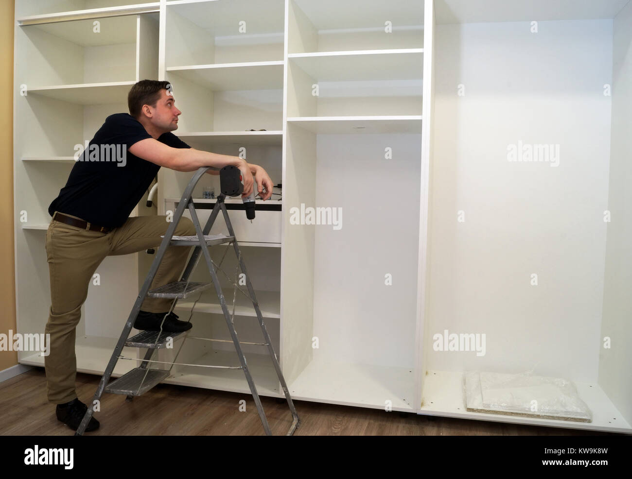Worker looking at wardrobe. Cabinet assembly concept. Stock Photo