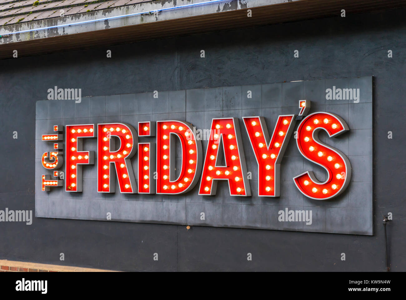 TGI Fridays restaurant chain illuminated logo/ sign in red letters outside a restaurant in the UK, January 2018 Stock Photo
