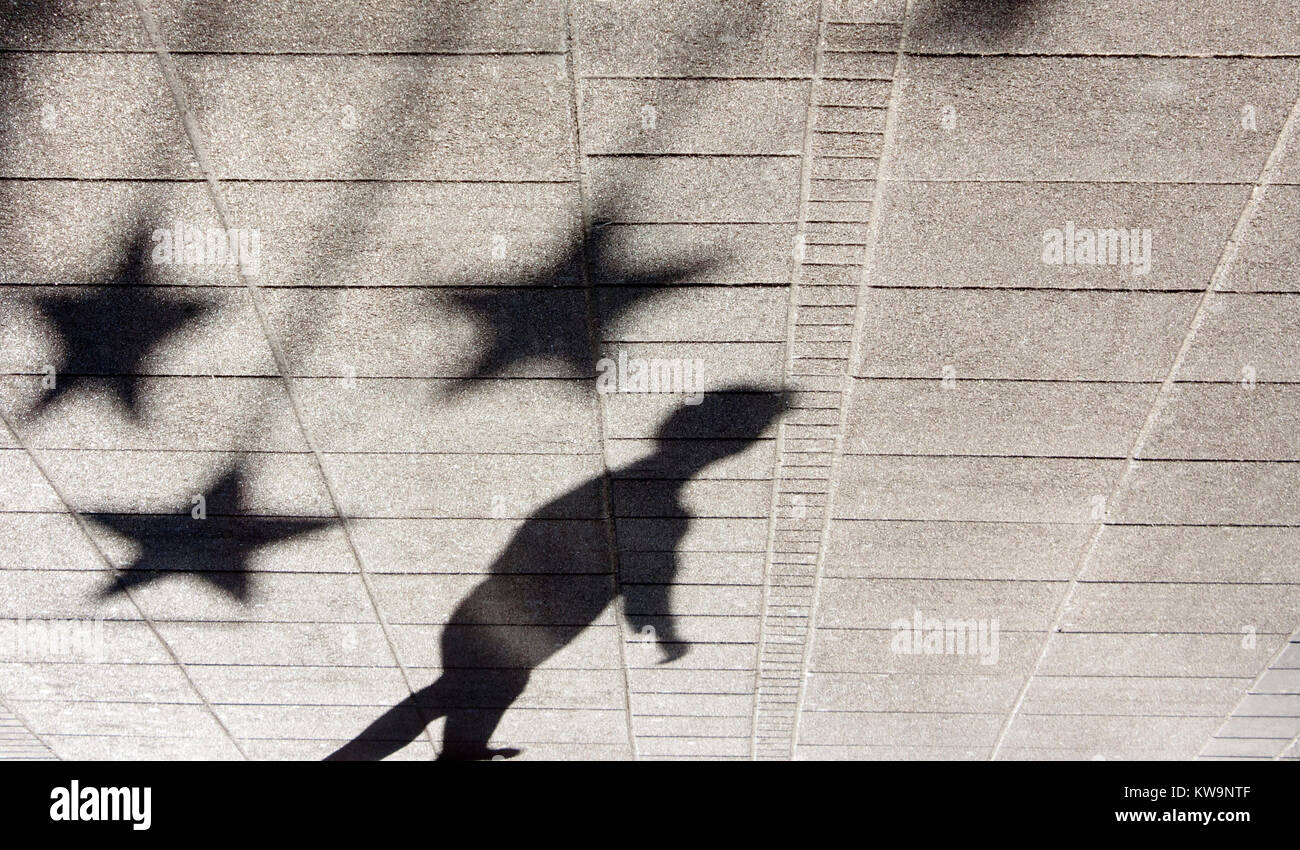 Shadow silhouette of a boy under star shaped ornaments on city street in black and white Stock Photo